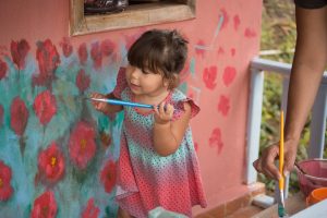 Menina pintando sua casinha de bonecas.