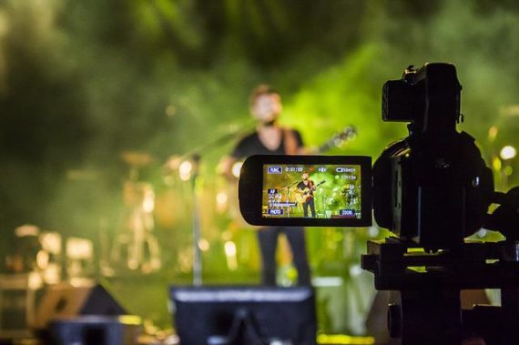 Imagem demonstra uma filmagem de uma cena com um homem e um guitarra
