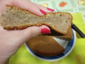 Bolo de castanhas. Uma fatia na mão da autora demonstrando a consistência do bolo assado